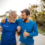 Deux coureurs souriants de marathon tenant une bouteille d'eau dans la main.
