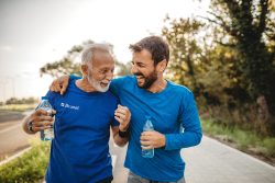 Deux coureurs souriants de marathon tenant une bouteille d'eau dans la main.