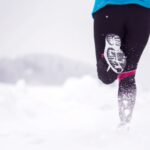 Vue d'une femme qui court dans un environnement enneigé.